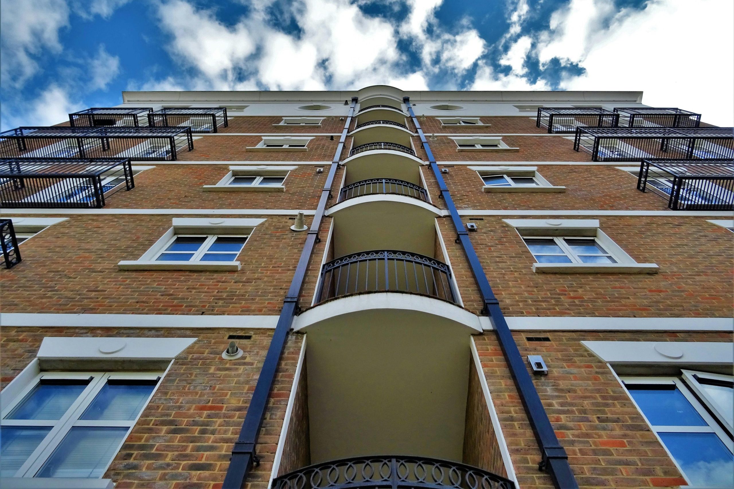 Low angle view of a modern urban apartment building with balconies under a clear blue sky.
